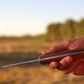 Hand holding a knife with a blurred natural background