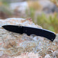 Black folding knife on a rock with a natural background