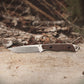 Folding knife with a brown handle on a wooden surface with a natural background