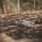 Multitool on a wooden log with a blurred natural background