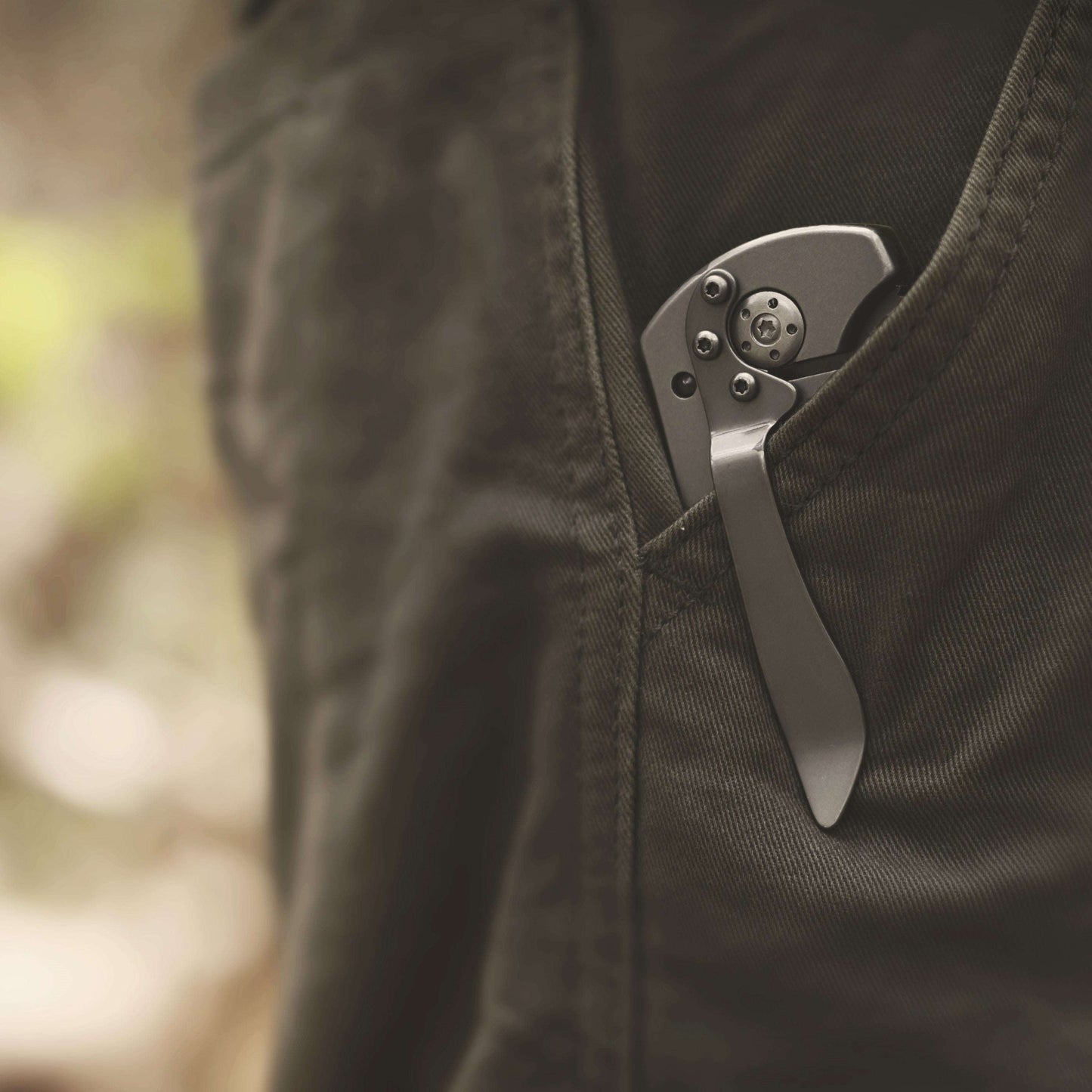 Folding knife in a pocket with a blurred natural background