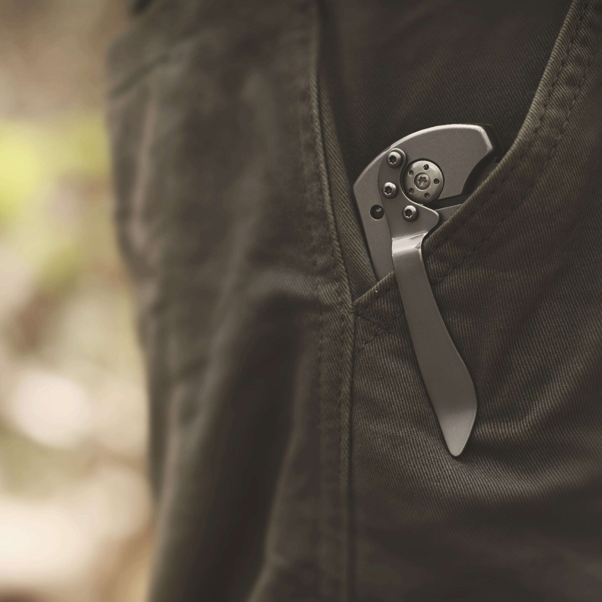Folding knife in a pocket with a blurred natural background