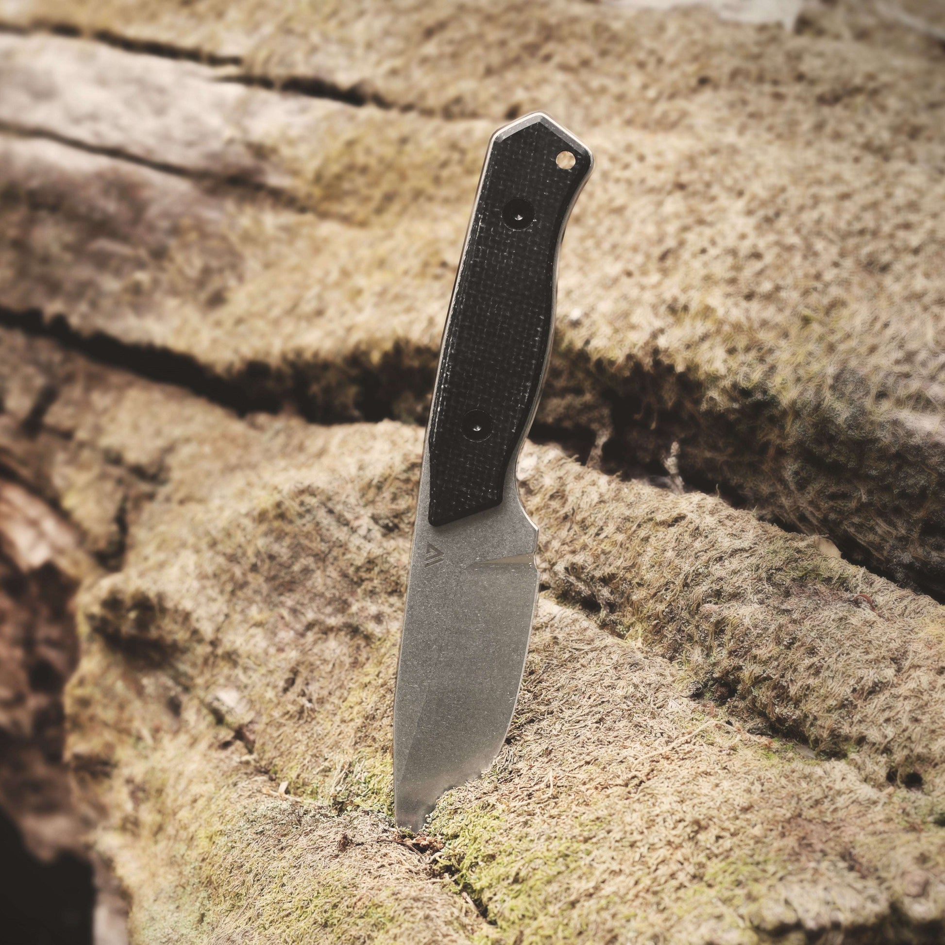 Knife with a black handle on a textured stone surface
