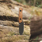 Folding knife with wooden handle on a mossy rock