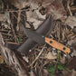 Knife with wooden handle and leather sheath on dry leaves